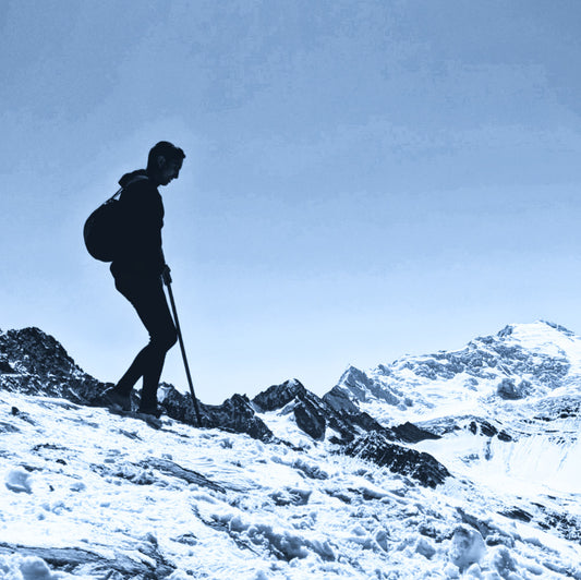 man wearing alpaca outdoor clothing hiking on a snow-covered hill